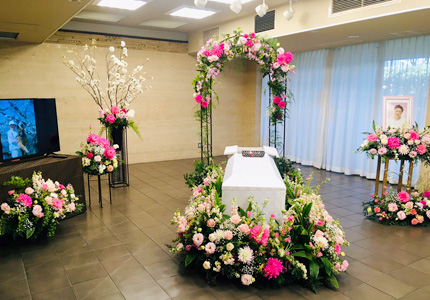 鮮やかなピンクの花で飾ったアーチが特徴の葬儀空間