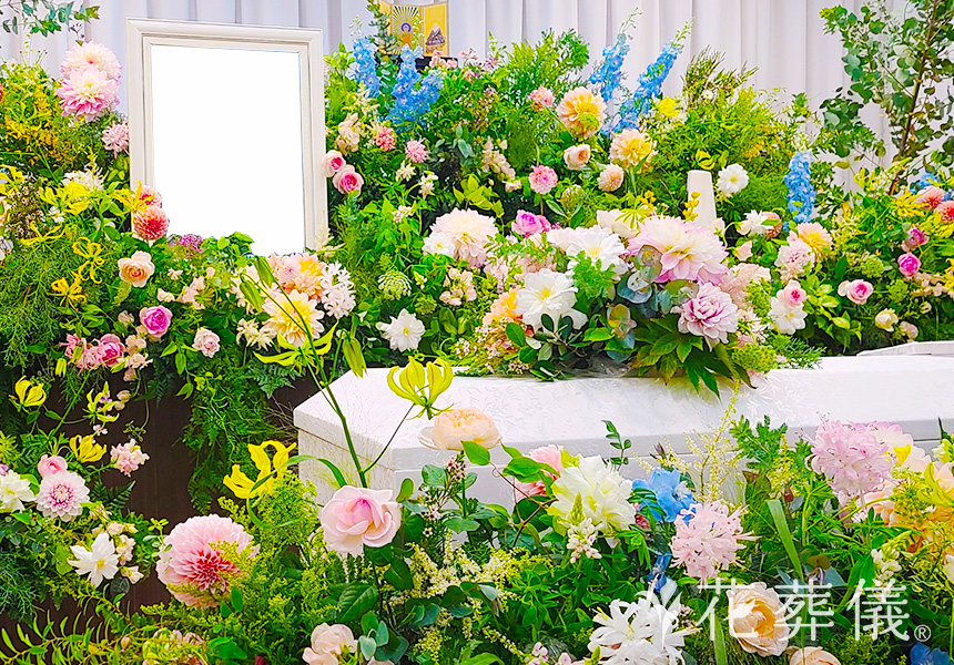 花祭壇の写真 グリーン、白、淡いピンク、黄色、淡いオレンジ等のあたたかい色合いで、かわいらしく自然のお花畑に眠っている空間をイメージして