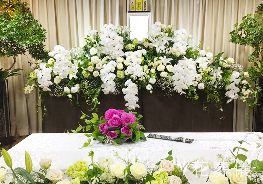 花の祭壇 バラ、ドウダンツツジ、胡蝶蘭、ユーカリなどのお花を白・グリーンの色合いで、家族カラーのピンクを棺上花としてお飾りした祭壇