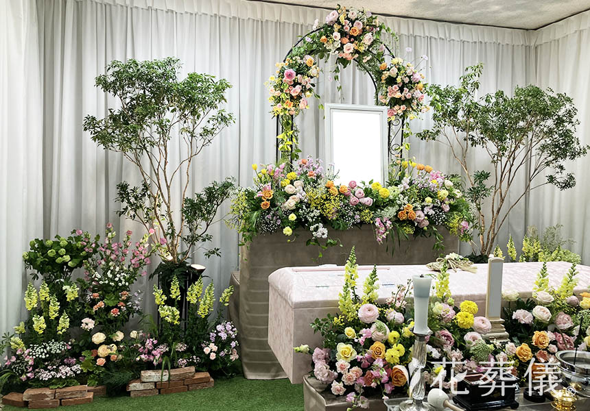 花祭壇の写真 淡いピンクや淡いオレンジ、ライトグリーンのお花とレンガや芝を使用した奥様のガーデニングを思わせる空間をイメージして
