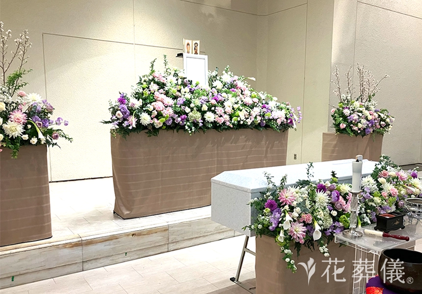 花祭壇のデザイン　丸いフォルムとシャープな印象のお花が白グリーン、淡ピンク、紫でのお色味でバランスよくデザインされた祭壇