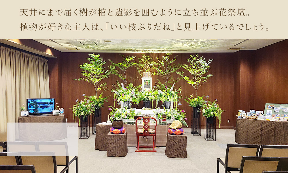 天井にまで届く樹が棺と遺影を囲むように立ち並ぶ花祭壇。植物が好きな主人は、「いい枝ぶりだね」と見上げているでしょう。