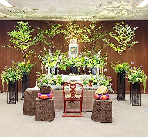 天井にまで届く樹が棺と遺影を囲むように立ち並ぶ花祭壇。植物が好きな主人は、「いい枝ぶりだね」と見上げているでしょう。