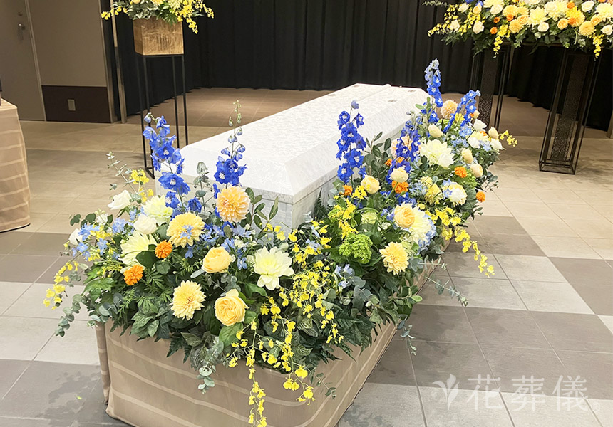 花祭壇の写真　優しく明るいお色味で、お父様の似顔絵も飾りした温かい空間をイメージした花祭壇