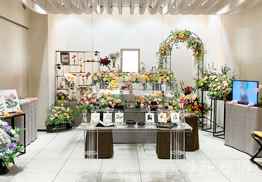 花葬儀の花祭壇　趣味で通っていた布絵教室で作った沢山の作品と、お好きだった花や季節の花とバラ園のイメージでバラのアーチを明るく華やかにお飾りした世界でたったひとつの花祭壇